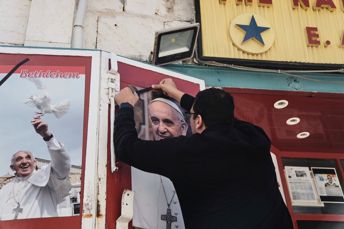 Un propietario de una tienda coloca un lazo negro sobre una foto del fallecido papa Francisco al conocer la noticia de su muerte a los 88 años, en Belén, Cisjordania, el lunes 21 de abril de 2025. (AP Foto/Mahmoud Illean)