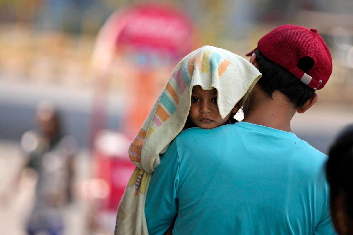 Un hombre carga a un niño, con la cabeza cubierta con una toalla para protegerlo del calor, en Jammu, India, el domingo 2 de junio de 2024. Una ola de calor extremo en la India mató a más de 100 personas el último mes. (Foto AP/Channi Anand, Archivo)