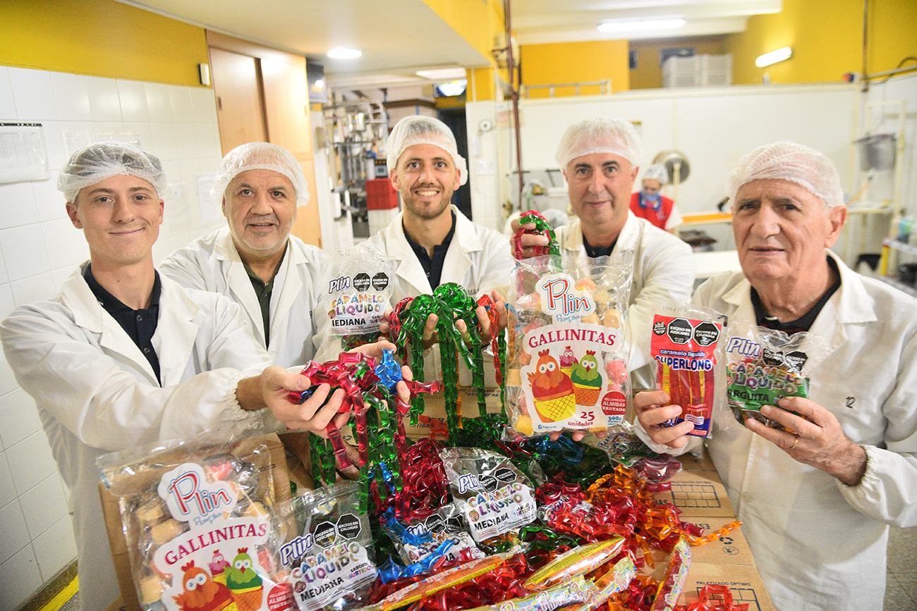 TRES GENERACIONES. "Kuki" Fermanelli junto a sus dos hijos, y sus dos nietos varones, que hoy llevan adelante la empresa. De izquierda a derecha, Ignacio, Néstor, Mariano, Gabriel y José Carlos "Kuki" Fermanelli muestran parte de la línea de golosinas de Plin. (La Voz) 