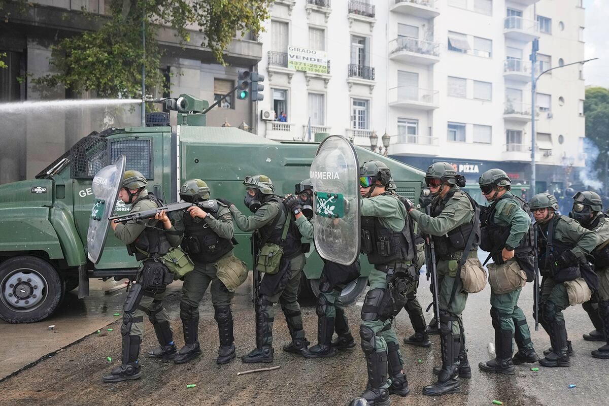 La policía sostiene escudos durante enfrentamientos contra las hinchadas que se unieron a jubilados. (AP)