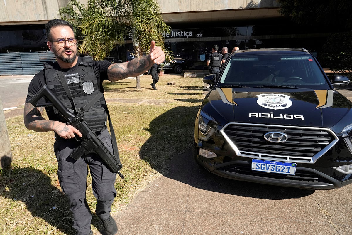 Agentes de la policía federal se encuentran en la oficina de la Secretaría de Administración Penitenciaria, donde se encuentra el expresidente brasileño Jair Bolsonaro, quien está siendo juzgado por un supuesto intento de golpe de Estado, después de que llegó para que le colocaran un grillete electrónico en Brasilia, Brasil, el viernes 18 de julio de 2025. (Foto AP/Eraldo Peres)