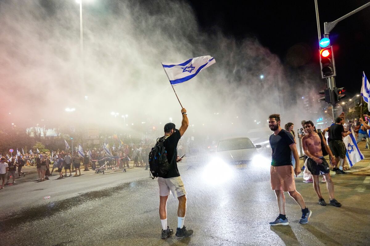 La policía israelí emplea un cañón de agua para dispersar a manifestantes que bloquean una calle en una protesta contra los planes del gobierno del primer ministro, Benjamin Netanyahu, de reformar el sistema judicial, en Jerusalén, el domingo 23 de julio de 2023. (AP Foto/Ohad Zwigenberg)