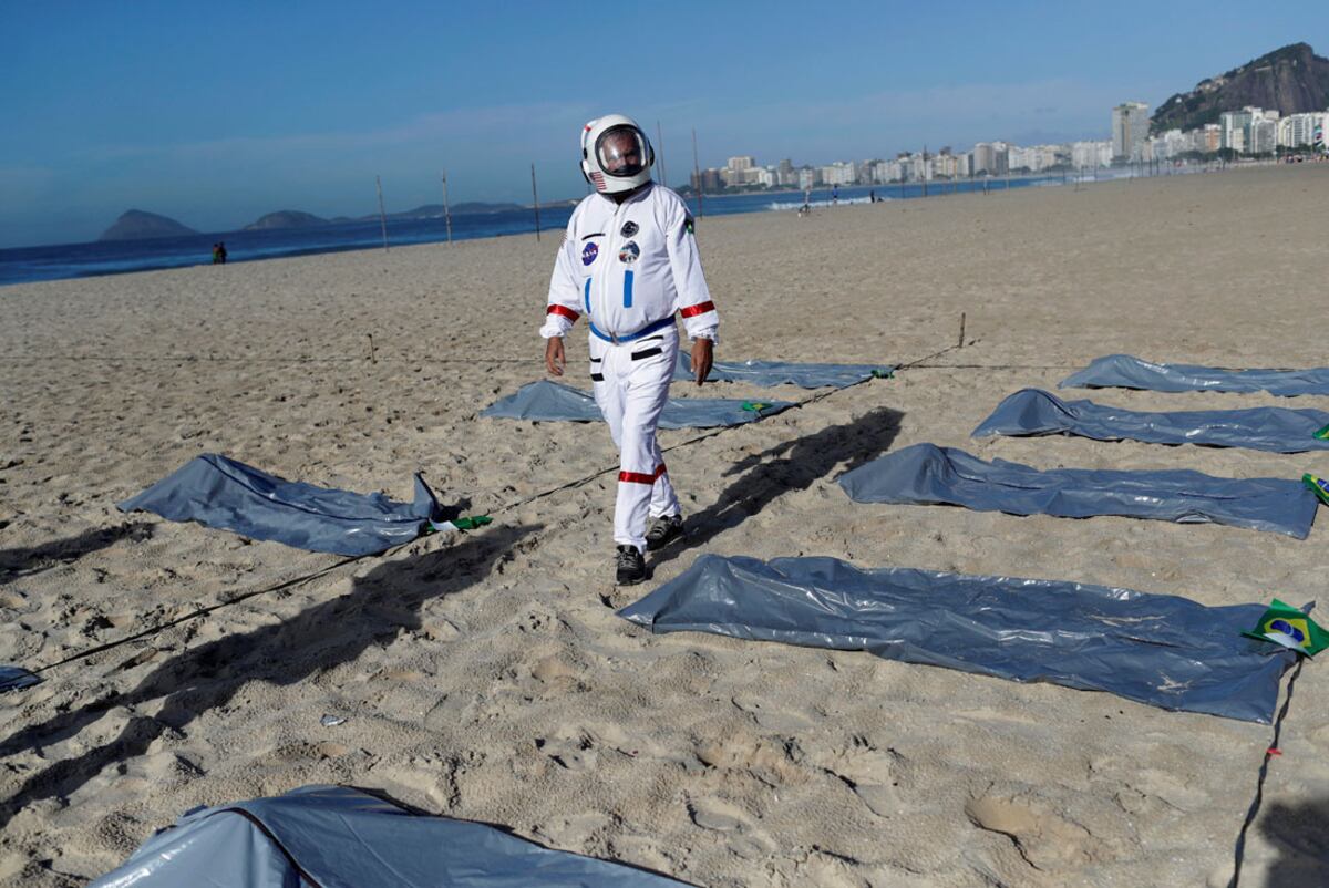 Un hombre y su traje de protección contra el virus, entre bolsas de cadáveres que simulan ser víctimas del Civid-19, en Río de Janeiro. (AP/Silvia Izquierdo)