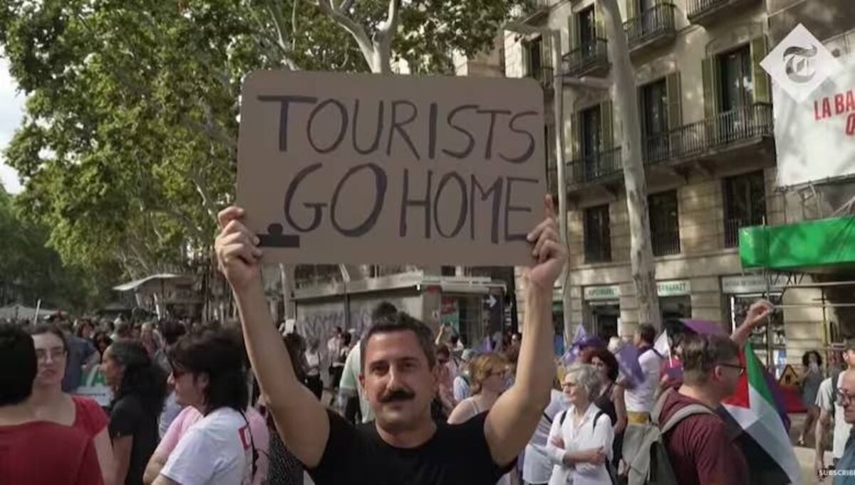 "Turistas vayánse a su casa". Manifestante con un cártel para los turistas.