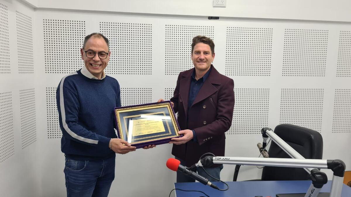 Omar Bustos, locutor de Radio Suquía, recibiendo la plaqueta en reconocimiento a su trayectoria.