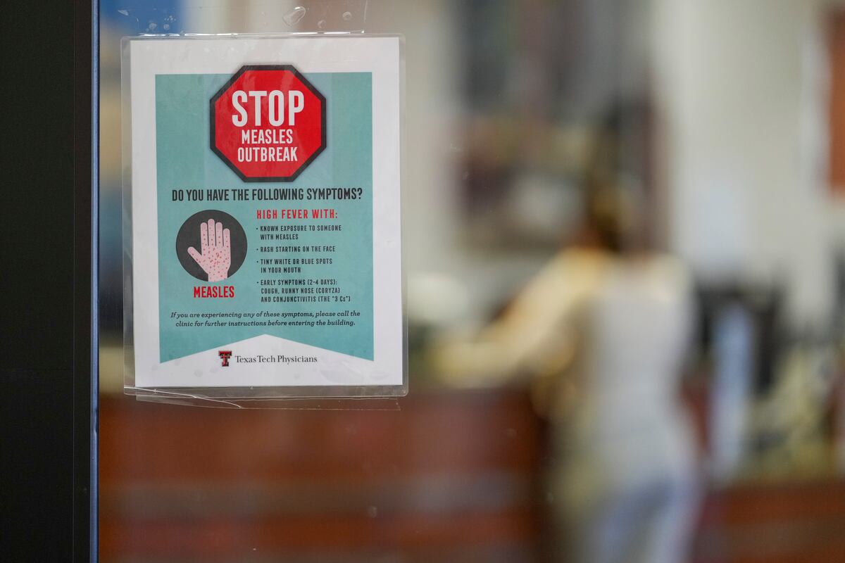 Un letrero de advertencia sobre el sarampión en una puerta de cristal, mientras una paciente llega a una cita en el área de medicina familiar en Texas Tech Physicians of the Permian Basin, el lunes 24 de febrero de 2025, en Odessa, Texas. (AP Foto/Julio Cortez)