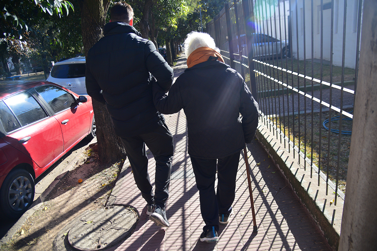 Nora camina por el barrio con Luis, el kinesiólogo que le da clases.
Foto: Pedro Castillo / La Voz