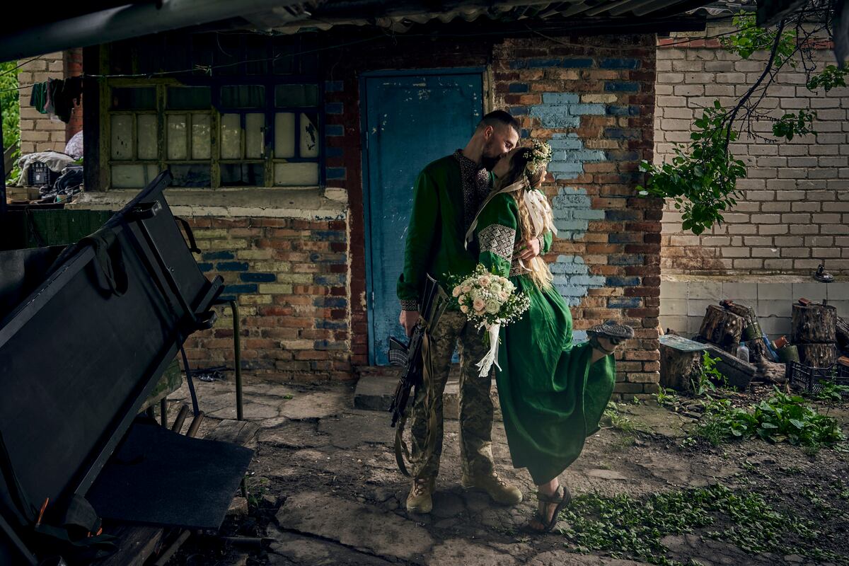 Médicos militares voluntarios, vestidos con atuendos nacionales, se besan durante su ceremonia de boda en su puesto en el frente en la región de Donetsk, Ucrania.