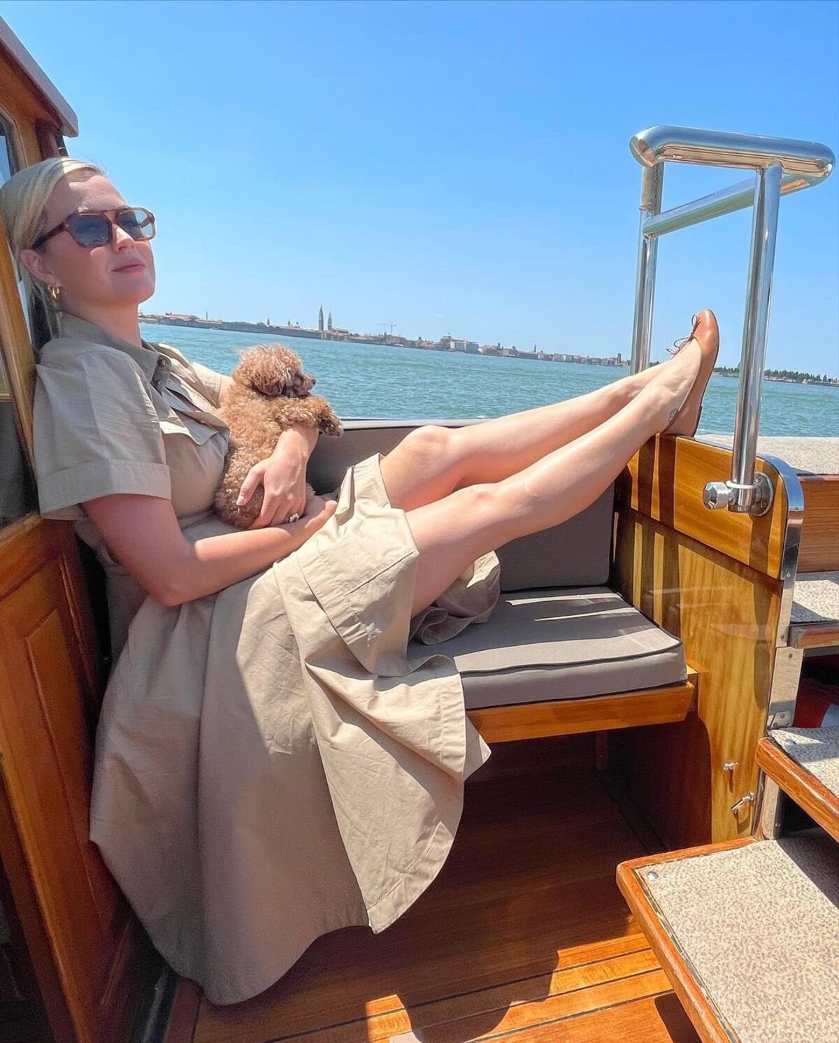 Katy disfruta del sol con su perrito e una embarcación en Venecia.