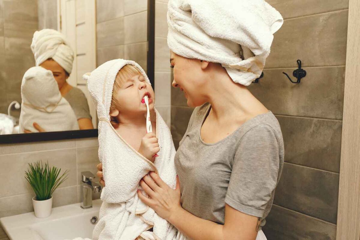 Family in a bathroom. Beautiful mother with little son. Little boy brush his teeth.