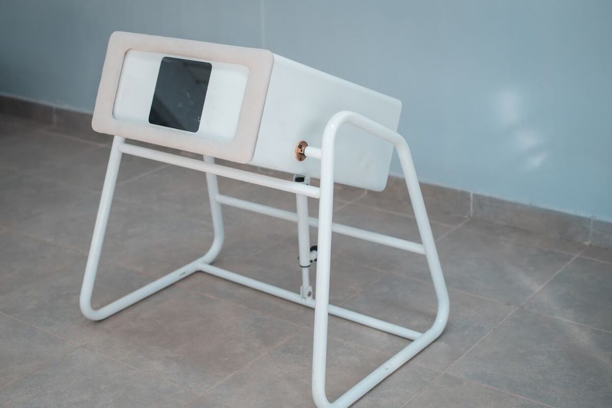 El aparto tiene una estación con una ventana transparente bajo la cual se coloca el sistema de medición, la paciente se sienta en una silla y se acuesta con los senos apoyados en la ventana. (MamoRef)