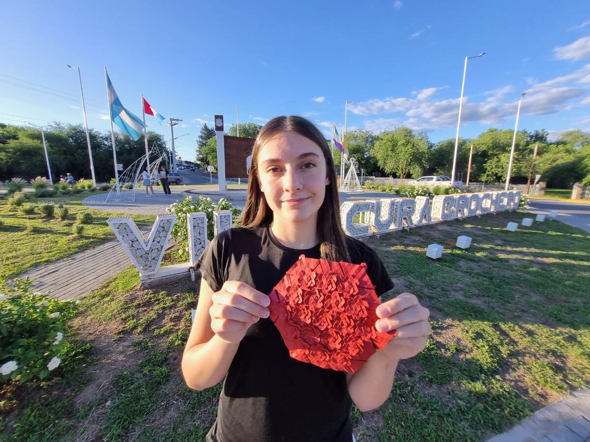 Angie, un origami en sus manos, con su Villa Cura Brochero de fondo (La Voz)