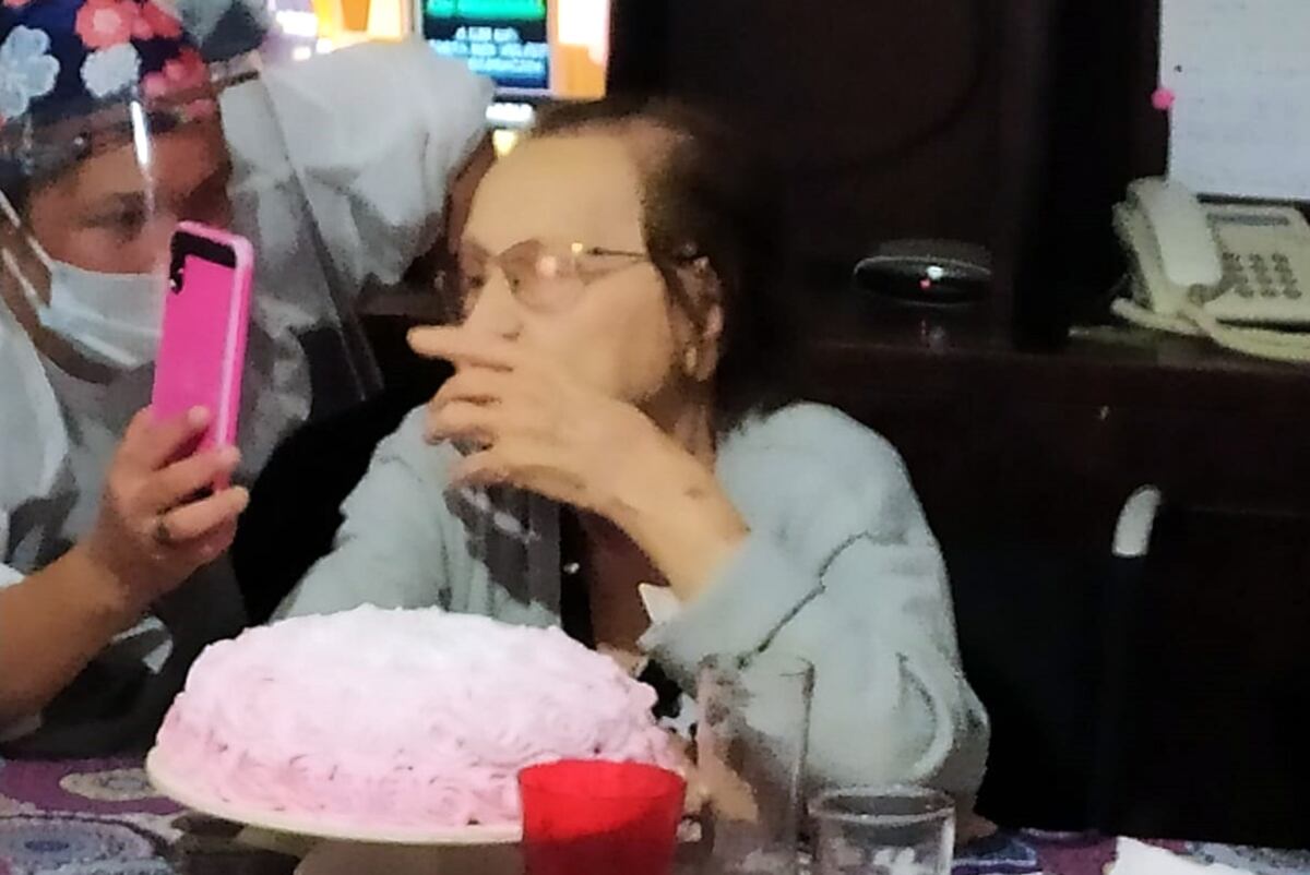 Una empleada de un hogar, le muestra el teléfono a una residente para contactarla por videollamada con sus familiares, en su cumpleaños.
(Gentileza Alba Barrera)